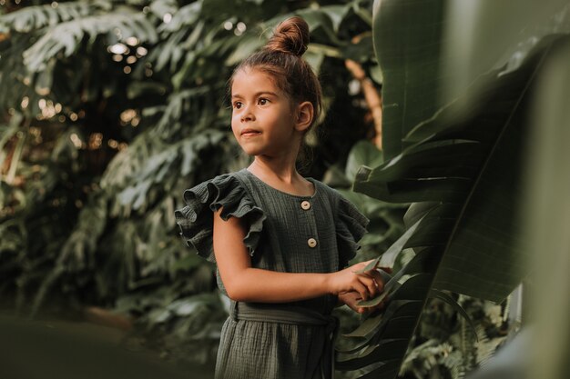 volto di una bambina circondata da foglie tropicali Ritratto in primo piano di un bellissimo bambino dalla carnagione scura