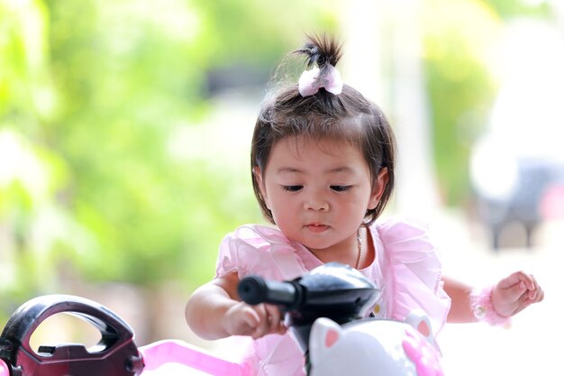 Volto di una bambina in bicicletta, Ritratto di un'adorabile bambina tailandese in sella a una bicicletta all'aperto.