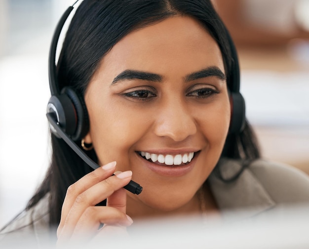 Volto e sorriso della donna nel call center per la consulenza di telemarketing o assistenza clienti in ufficio Consulente dipendente femminile felice che sorride con l'auricolare in comunicazione per il servizio online o aiuto