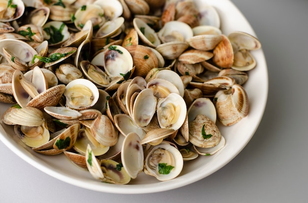 Vongole al vapore in salsa di aglio in una ciotola bianca. Avvicinamento