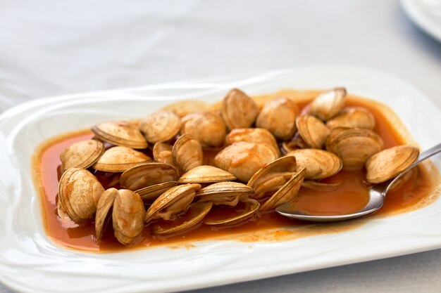 Vongole con salsa sul piatto bianco.