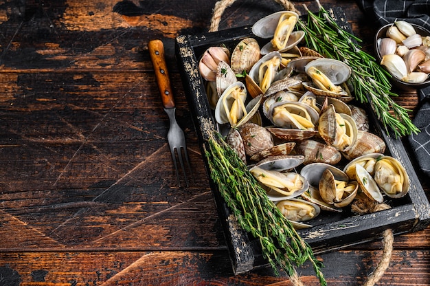 Vongole di vongole in un vassoio di legno con erbe aromatiche