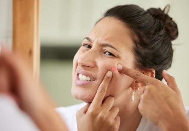 Vorrei avere una soluzione più permanente Inquadratura di una donna che spreme un brufolo mentre si guarda nello specchio del bagno