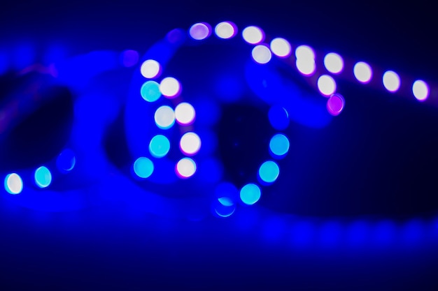 Vortice sfocato al neon viola e blu di luci a led bokeh su sfondo nero Festa notturna astratta