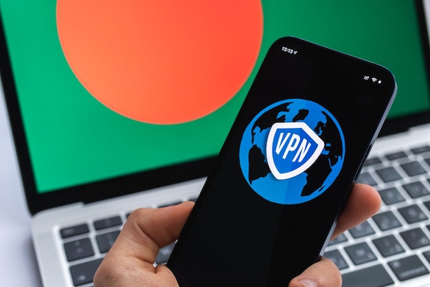 VPN in Bangladesh Concetto di Internet sicuro e sicuro Privacy Mano con telefono cellulare e applicazione VPN Bandiera e laptop sulla foto di sfondo