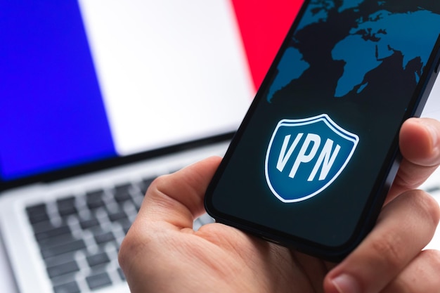 VPN in Francia Concetto di Internet sicuro e sicuro Privacy Mano con telefono cellulare e applicazione VPN Bandiera e laptop sulla foto di sfondo