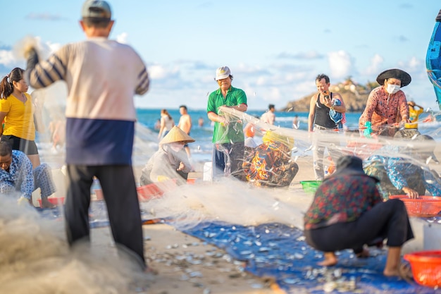 Vung Tau VIETNAM 14 MAGGIO 2023 Pescatore che getta la rete all'alba o al tramonto I pescatori tradizionali preparano la rete da pesca