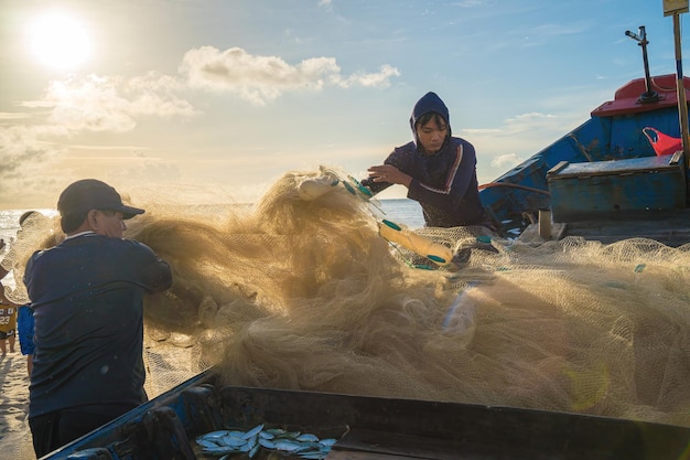 Vung Tau VIETNAM 20 AGOSTO 2022 Pescatore che getta la sua rete all'alba o al tramonto I pescatori tradizionali preparano la rete da pesca I pescatori sulla spiaggia alla pesca