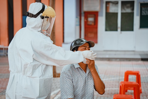 Vung Tau VIETNAM 28 NOVEMBRE 2021 Focus L'operatore sanitario con dispositivi di protezione bianchi esegue un tampone di coronavirus sulla donna Tampone nasale per Covid19 Medico che esegue il test PCR all'aperto