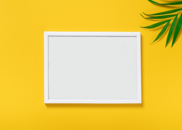 Vuoto mock up photo frame su sfondo giallo, foglie di palma tropicale