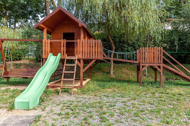 Vuoto moderno in legno parco giochi per bambini impostato su cortile verde in un parco pubblico in giornata estiva. Terra giocattolo divertente per i bambini. Attività di esercizio urbano per bambini all'aperto. Concetto di infanzia di quartiere.