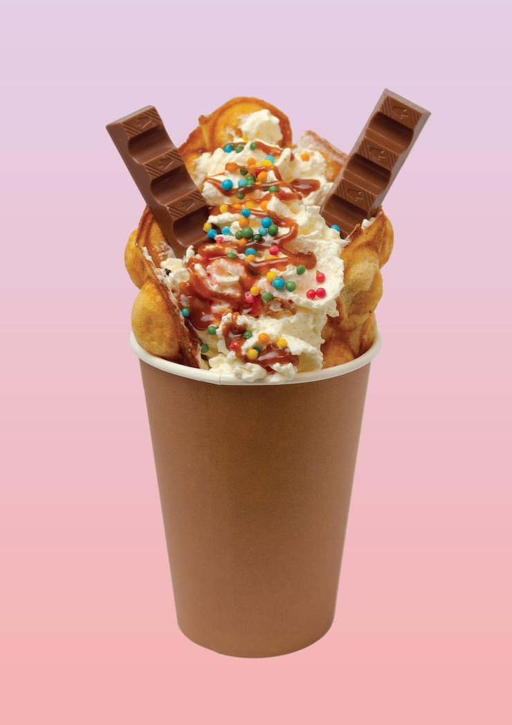 Foto waffle a bolle con whipped cream, gelati, caramelle e cioccolato.