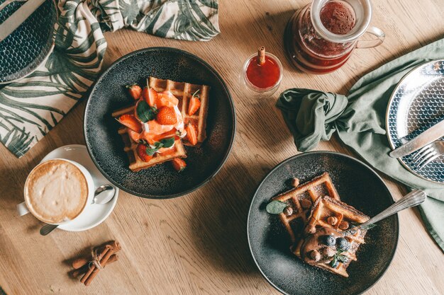 Waffle belgi con frutti di bosco, gelato e cioccolato. Impostazione del tavolo per la colazione. Stile di vita mattutino.