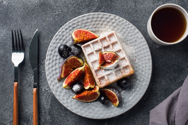 Waffle belgi tradizionali con uva e fichi di zucchero a velo.