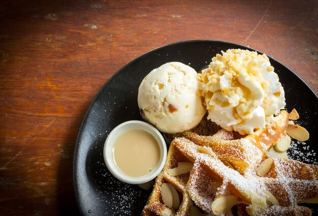 Waffle con gelato sul piatto nero.