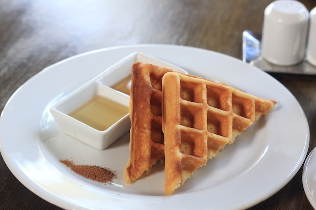 Waffle con sciroppo d&#39;acero Cannella in polvere sul piatto bianco