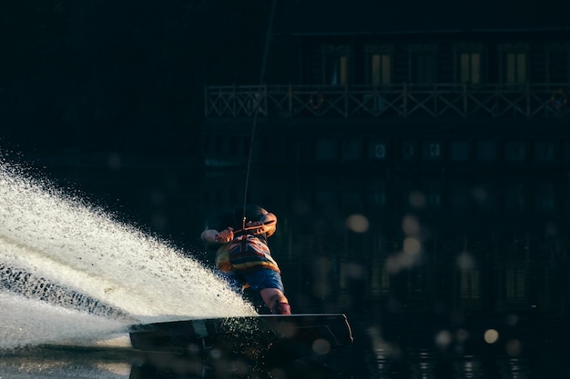 Wakeboard, wakeboarder scivola sull'acqua con wakeboard e creando schizzi, sfondo nero