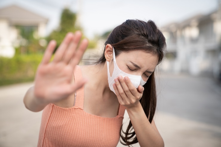 Photo wanita merasa sakit, batuk atau bersin. memegang tangan di depannya, tanda untuk berhenti. dia mengenakan masker pelindung.