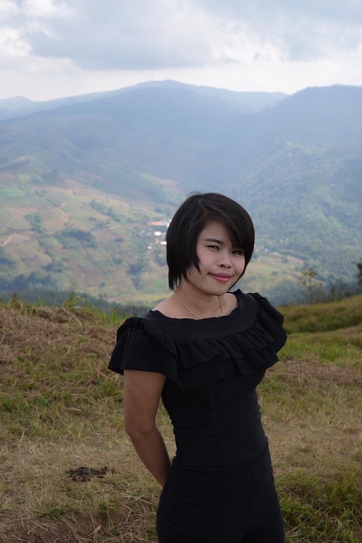 Photo wanita muda berdiri di ladang dengan latar belakang pegunungan