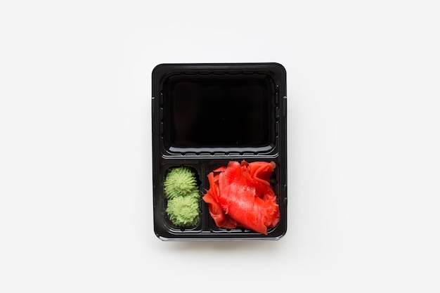 wasabi allo zenzero con salsa di soia in una ciotola di plastica nera isolata su uno sfondo bianco
