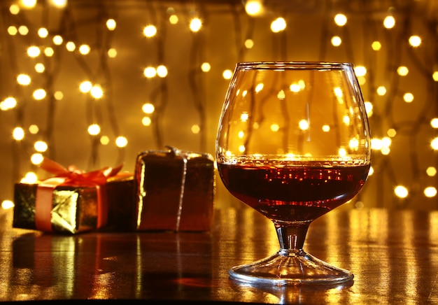 Whisky, cognac, brandy e confezione regalo sul tavolo di legno. Celebrazione composizione sulla luce