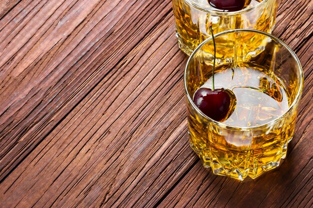 Whisky con ghiaccio e ciliegia in due bicchieri