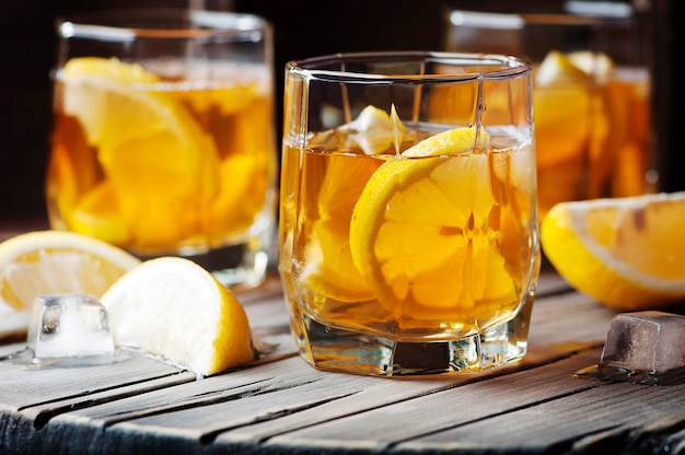 Whisky freddo con ghiaccio e limone sul tavolo vintage