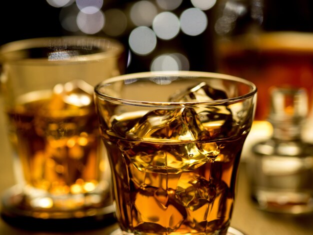 Whisky on the rocks con una stringa di luci sfocate sullo sfondo per creare un'atmosfera vacanziera