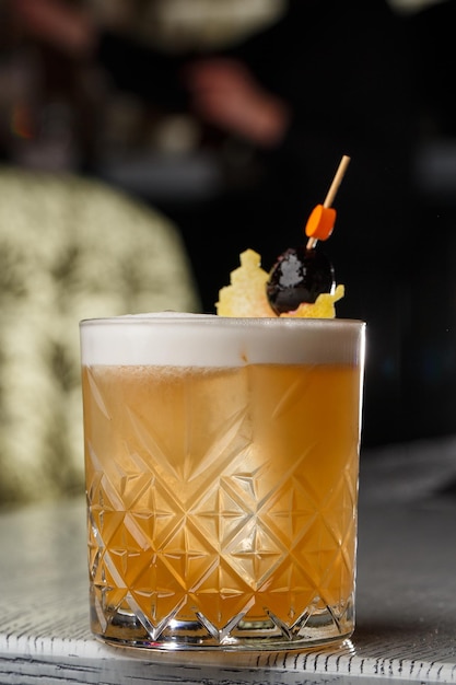 Whisky Sour cocktail alcolico con fetta d'arancia e cubetti di ghiaccio su sfondo scuro