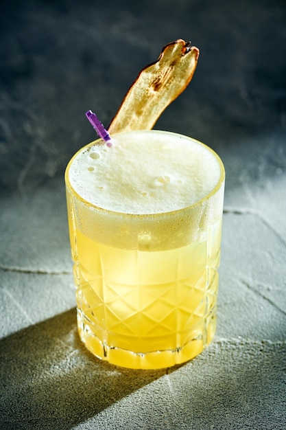 Whisky Sour cocktail con tuorlo d'uovo su uno sfondo di cemento Cocktail alcolico giallo con luce dura