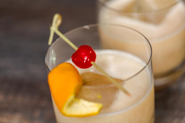 Whisky Sour Cocktail guarnito con arancia e ciliegia.