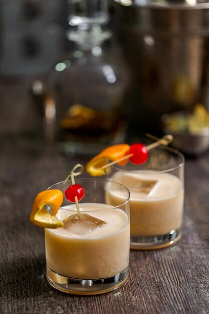 Whisky sour cocktail guarnito con arancia e ciliegia.