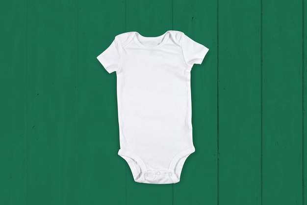 White Baby Onesie Mockup su sfondo di legno verde allegro