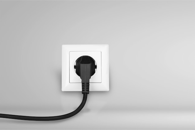White electrical plug in the electric socket on a wall