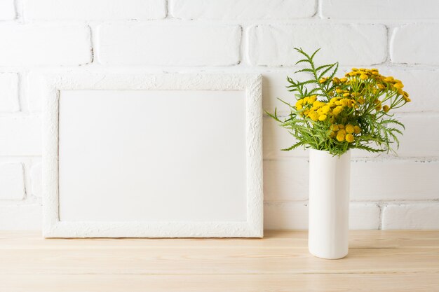 White frame mockup with yellow flowers near painted brick walls