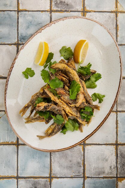 Whitebait Pesce e limone e piatto bianco Un piccolo piatto di bianchetti fritti con fettine di limone