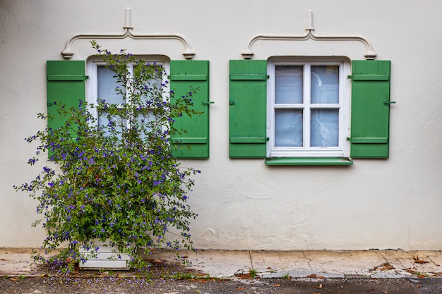 Windows con gli otturatori verdi in vecchia costruzione bianca tradizionale in Baviera, Germania