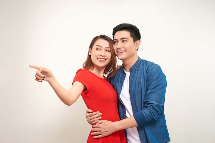 Photo woman points at something. both lovers looking at camera. isolated on white background