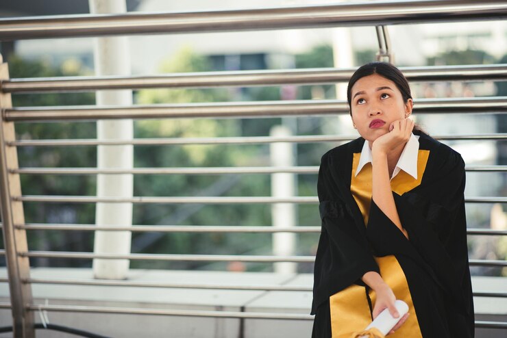Photo woman with hand on chin looking away while kneeling against railing