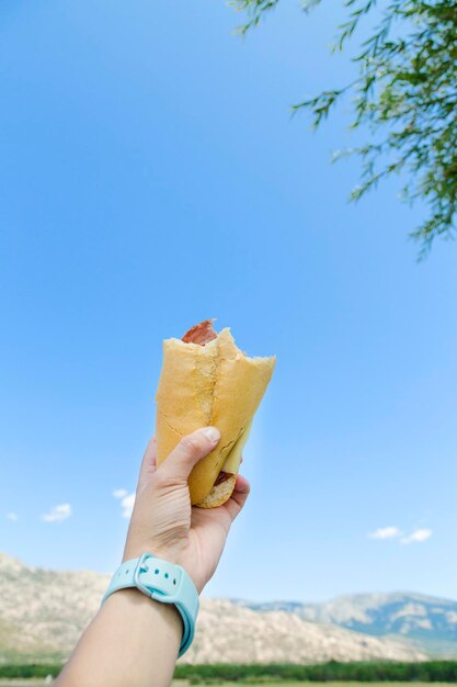 Womans mano con un panino e il cielo sullo sfondo Cibo sano per ripristinare l'energia