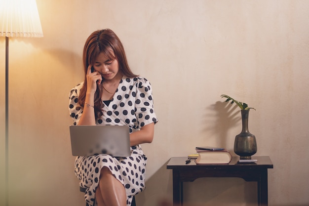 Workwoman dell&#39;Asia che utilizza computer portatile nel caffè con felice