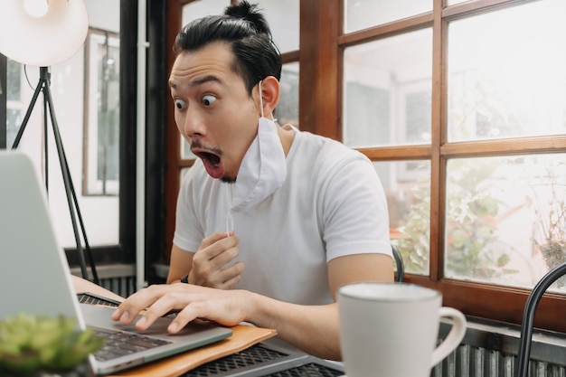 Wow e la faccia sorpresa dell'uomo lavora con il suo laptop