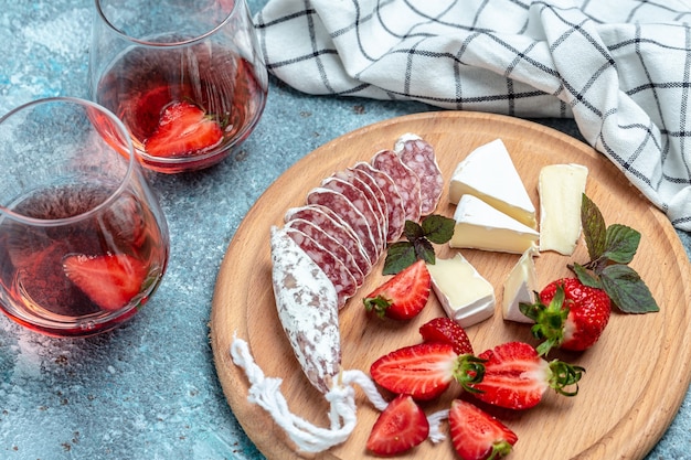 Wurst di salame spagnolo Fuet con formaggio Camembert, fragole. Sfondo di ricetta alimentare. Avvicinamento.