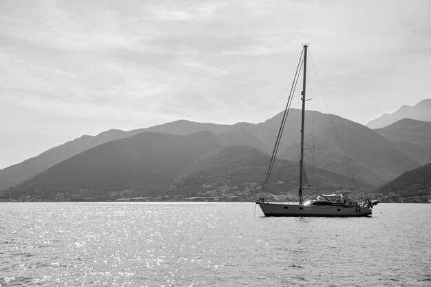 Yacht a vela con albero alto in mare al largo della riva. Paesaggio marino, fotografia in bianco e nero