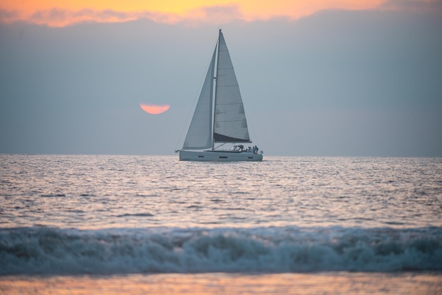 Yacht a vela contro il paesaggio al tramonto con skyline di barche a vela e silhouette al tramonto turismo da diporto ...