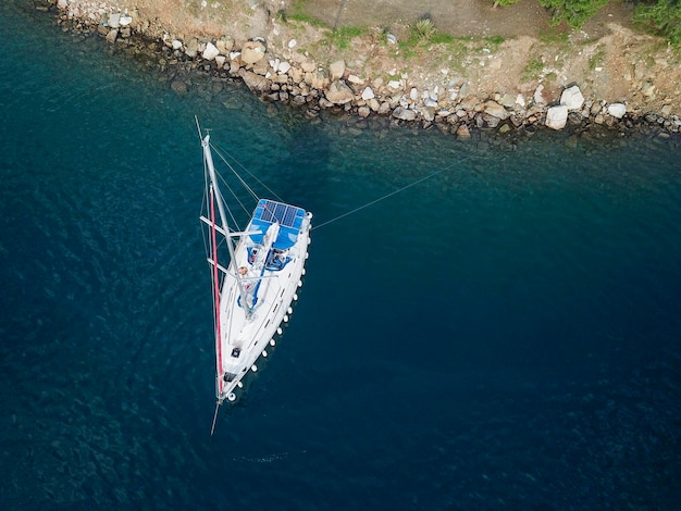 Yacht a vela senza vele all'ancora e alla linea di ormeggio in mare vista aerea da drone Acqua di mare blu