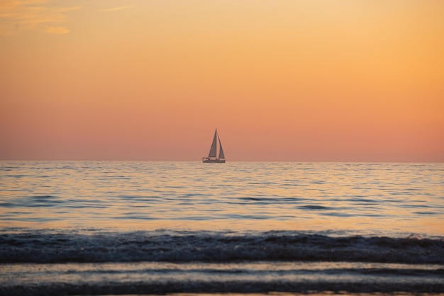 Yacht a vela sull'alba sul mare e sul bellissimo tramonto colorato sulla spiaggia dell'oceano