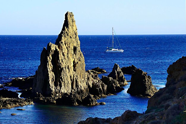 Yacht a vela vicino alle formazioni costiere rocciose in mare