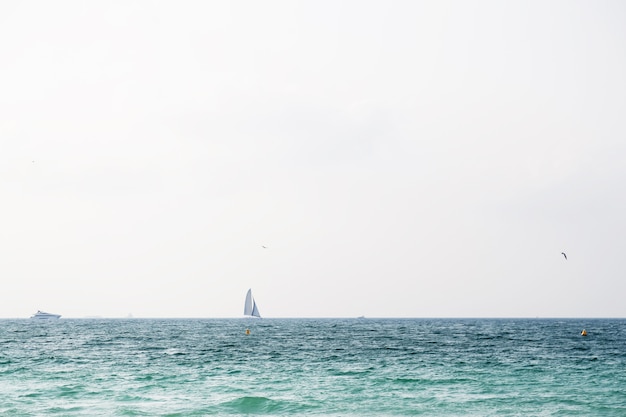 Yacht all'orizzonte in mare con cielo azzurro e nuvole.