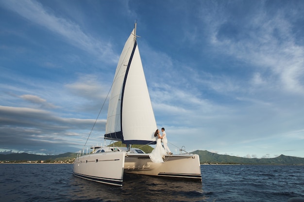 Yacht bianco con set di vele percorre l'isola in una giornata calda.